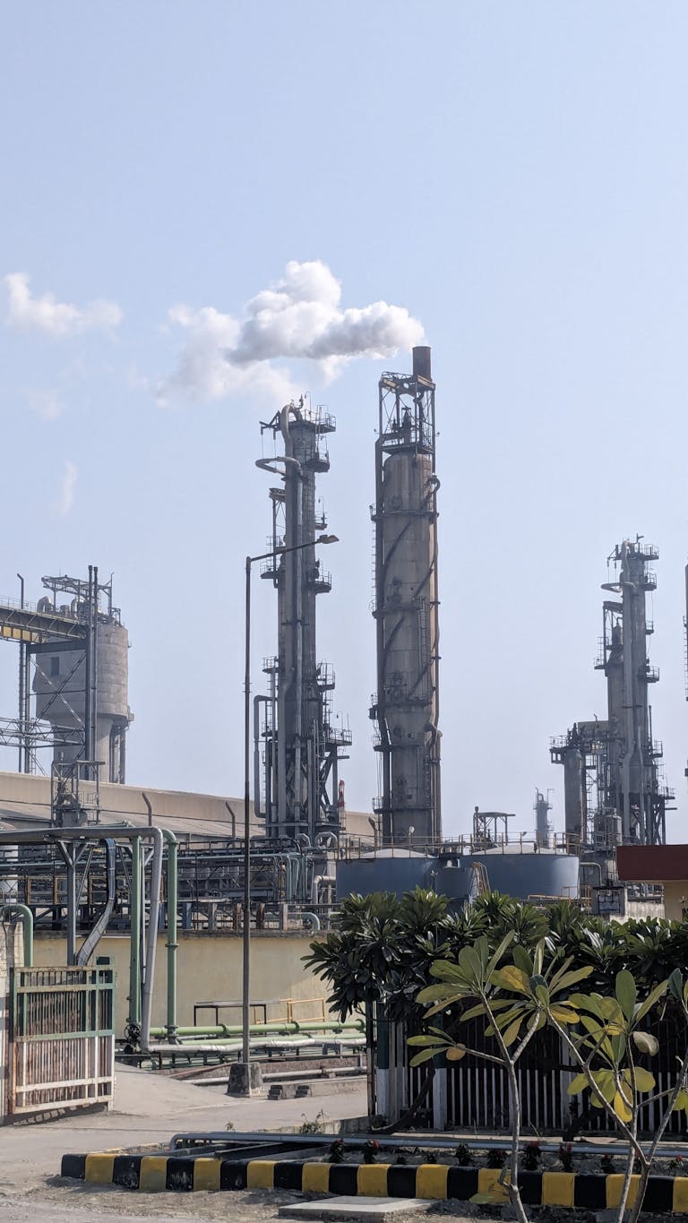 A detailed view of a chemical plant's tall chimneys and industrial structures against a clear sky.